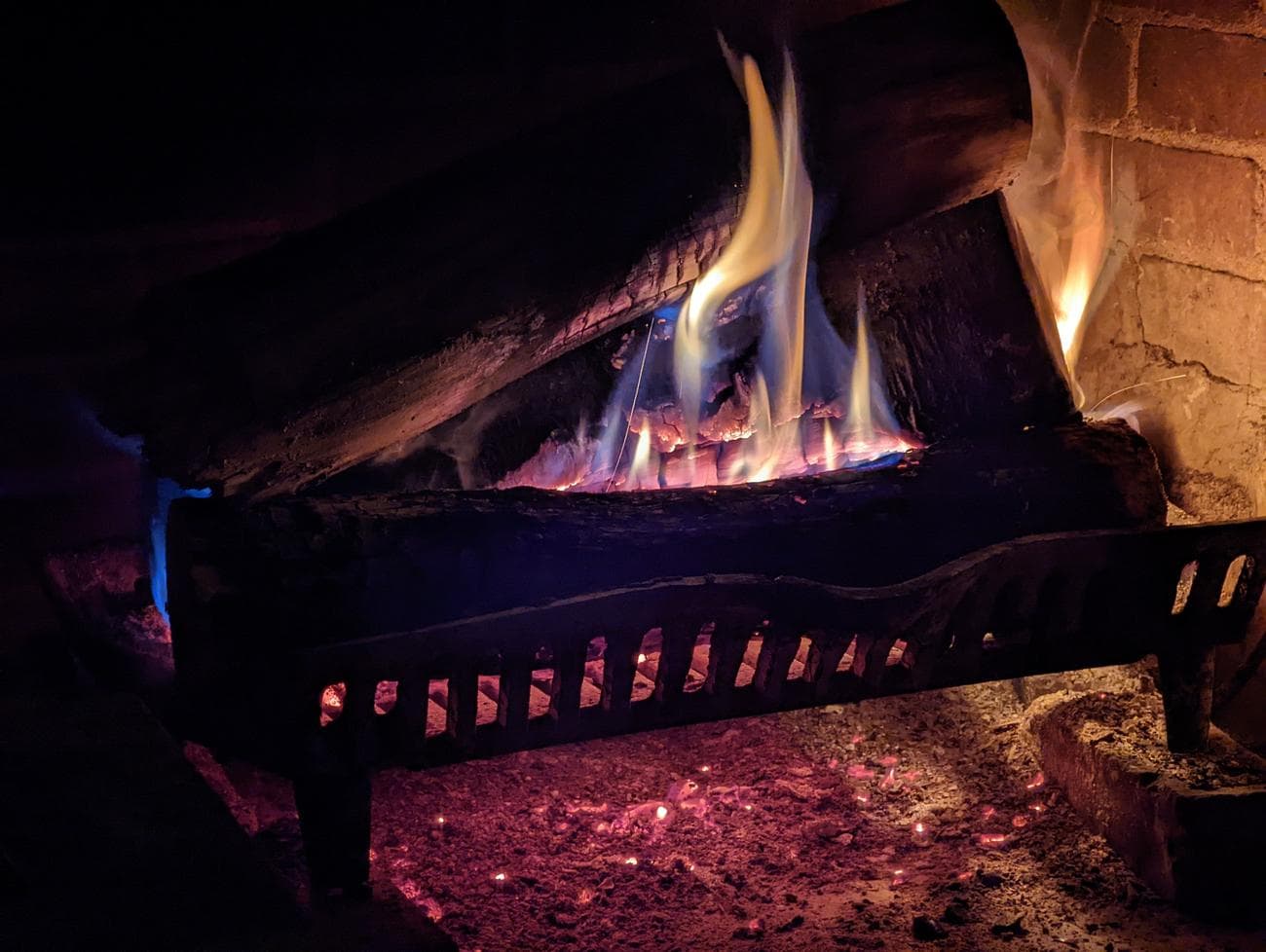 Φωτογραφία ενός τζακιού όπου η φλόγα καίει λίγο πιο έντονα, φωτίζοντας τη σκηνή γύρω του