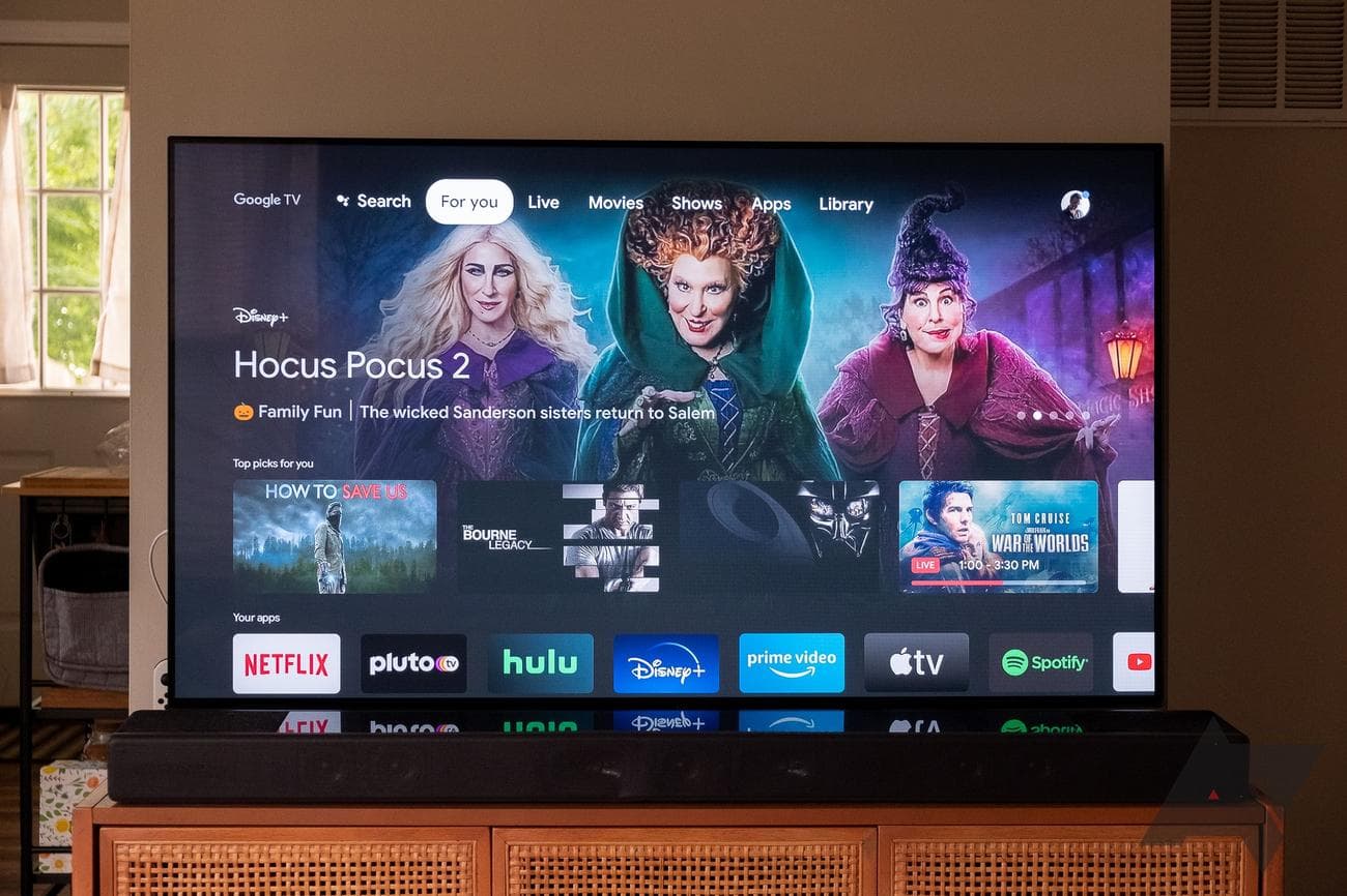 Μια μεγάλη τηλεόραση σε βάση σε ένα σπίτι με την αρχική οθόνη του Google TV να εμφανίζεται.