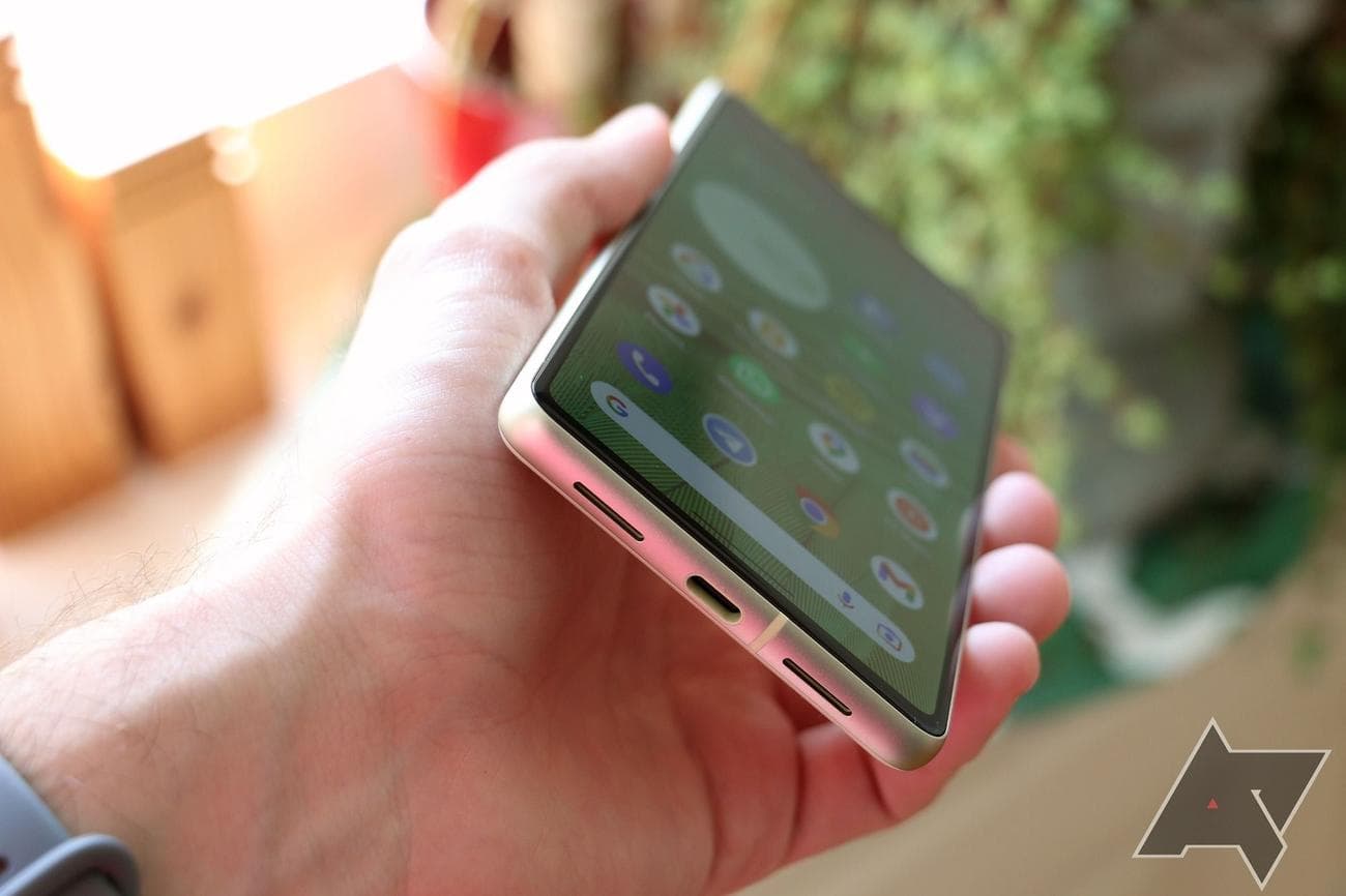 The Google Pixel 7's bottom with speaker grills and USB-C dock, phone held in hand at an angle.