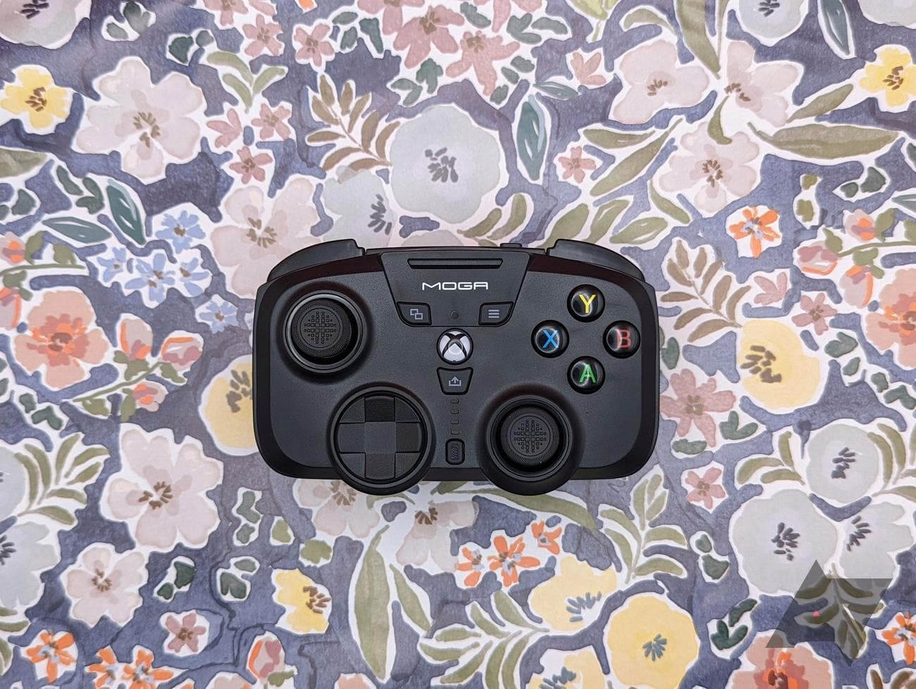 μαύρο χειριστήριο παιχνιδιών που στηρίζεται σε λουλουδάτο φόντο