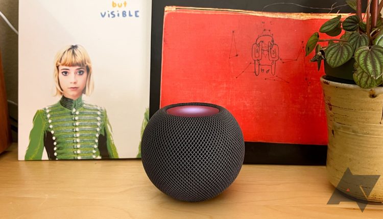 Apple HomePod mini set on a table with vintage record, art, and a plant