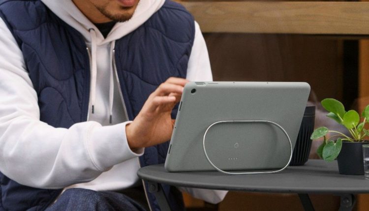 tablet resting on kickstand facing away from camera while man in blue and white jacked taps it