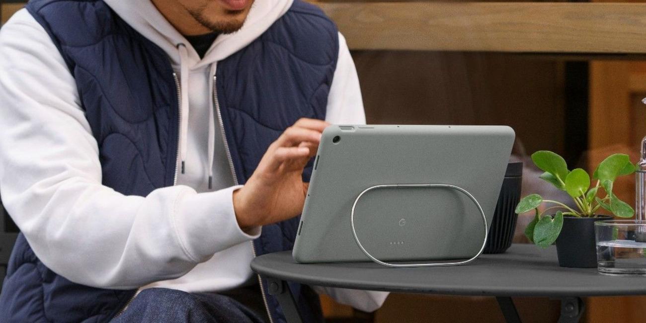 tablet resting on kickstand facing away from camera while man in blue and white jacked taps it