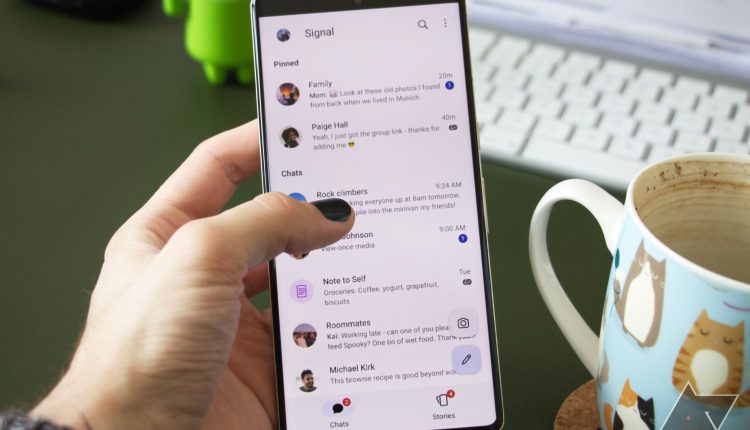 A person is holding a Google Pixel 7 Pro, interacting with the Signal chat overview