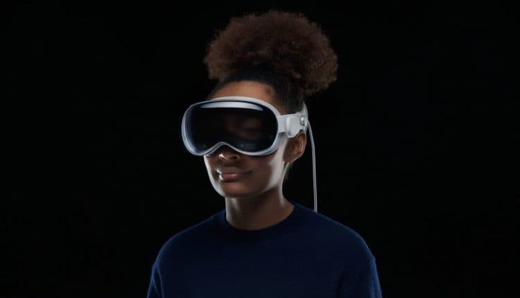 A woman wearing the Apple Vision Pro headset in front of a black background