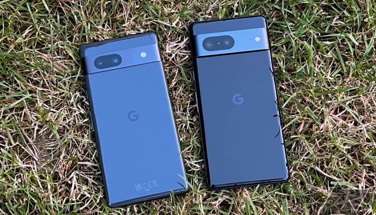 A black Google Pixel 7a and a black Pixel 7 lying display-down on grass next to each other