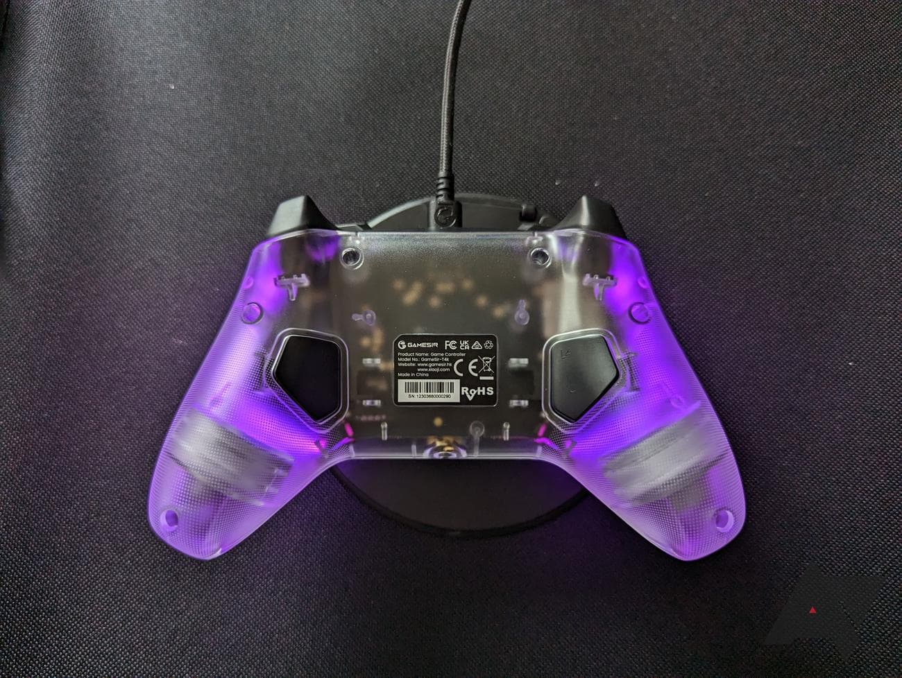 πίσω μέρος του καθαρού χειριστηρίου παιχνιδιών με μωβ φωτισμό σε μαύρο φόντο