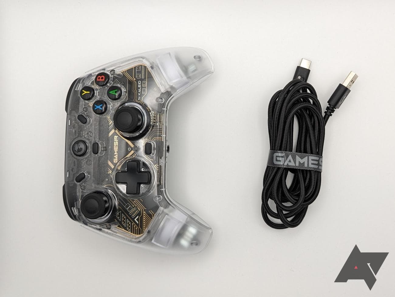 καθαρό χειριστήριο παιχνιδιών και μαύρο καλώδιο σε άσπρο φόντο