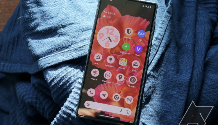 A smartphone sit rests on top of a blue woven fabric. 