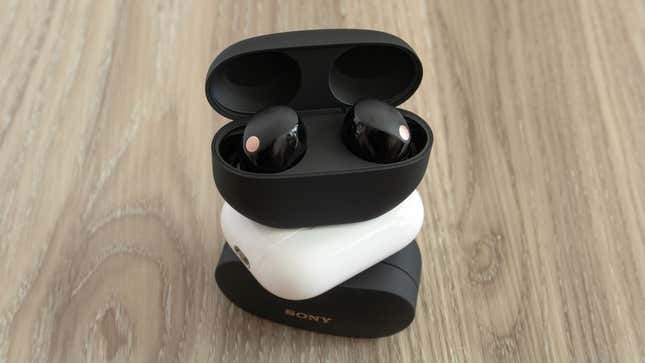 A stack of wireless earbud charging cases with the new Sony Sony WF-1000XM5 on top with the lid open.