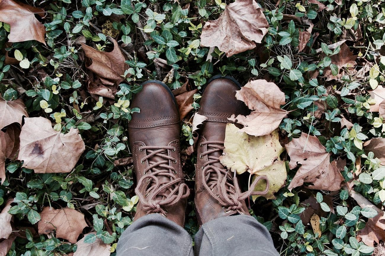 boots standing on grass with leaves around them
