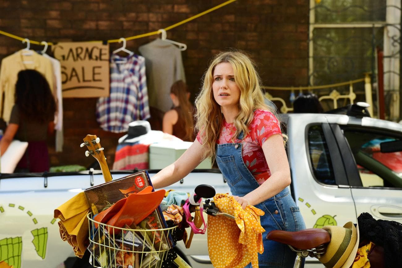 Η Ashley στέκεται περιτριγυρισμένη από τα υπάρχοντά της με το σημάδι 