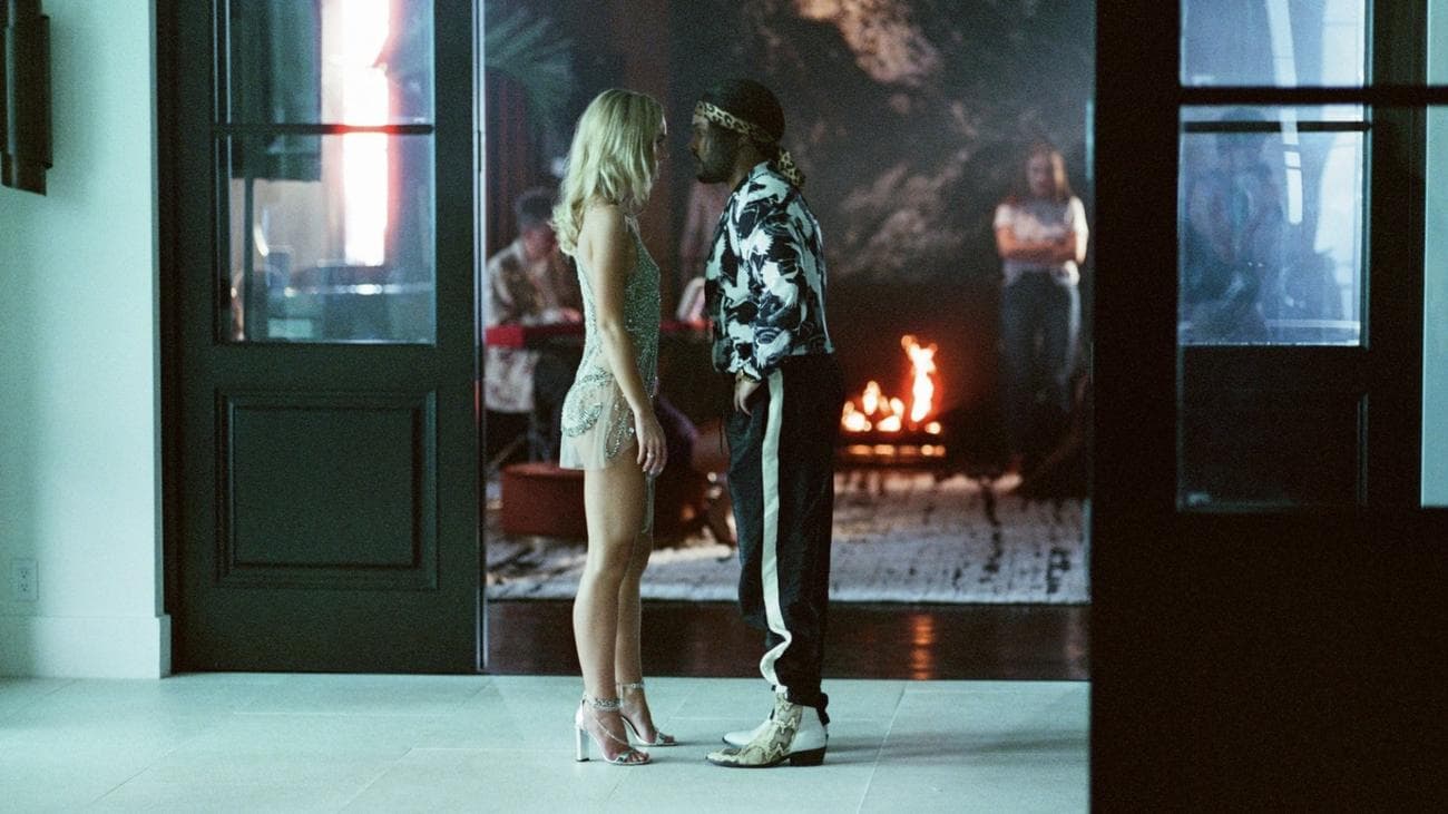 Μια γυναίκα με ένα καθαρό αστραφτερό φόρεμα και ένας άντρας με ένα ασπρόμαυρο πουκάμισο μαλώνουν σε έναν διάδρομο.