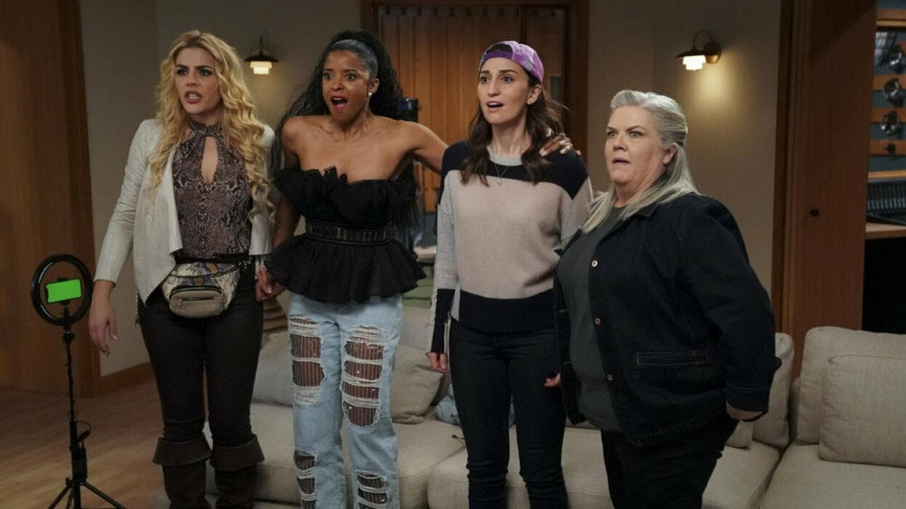 Four women stand together looking happily surprised.