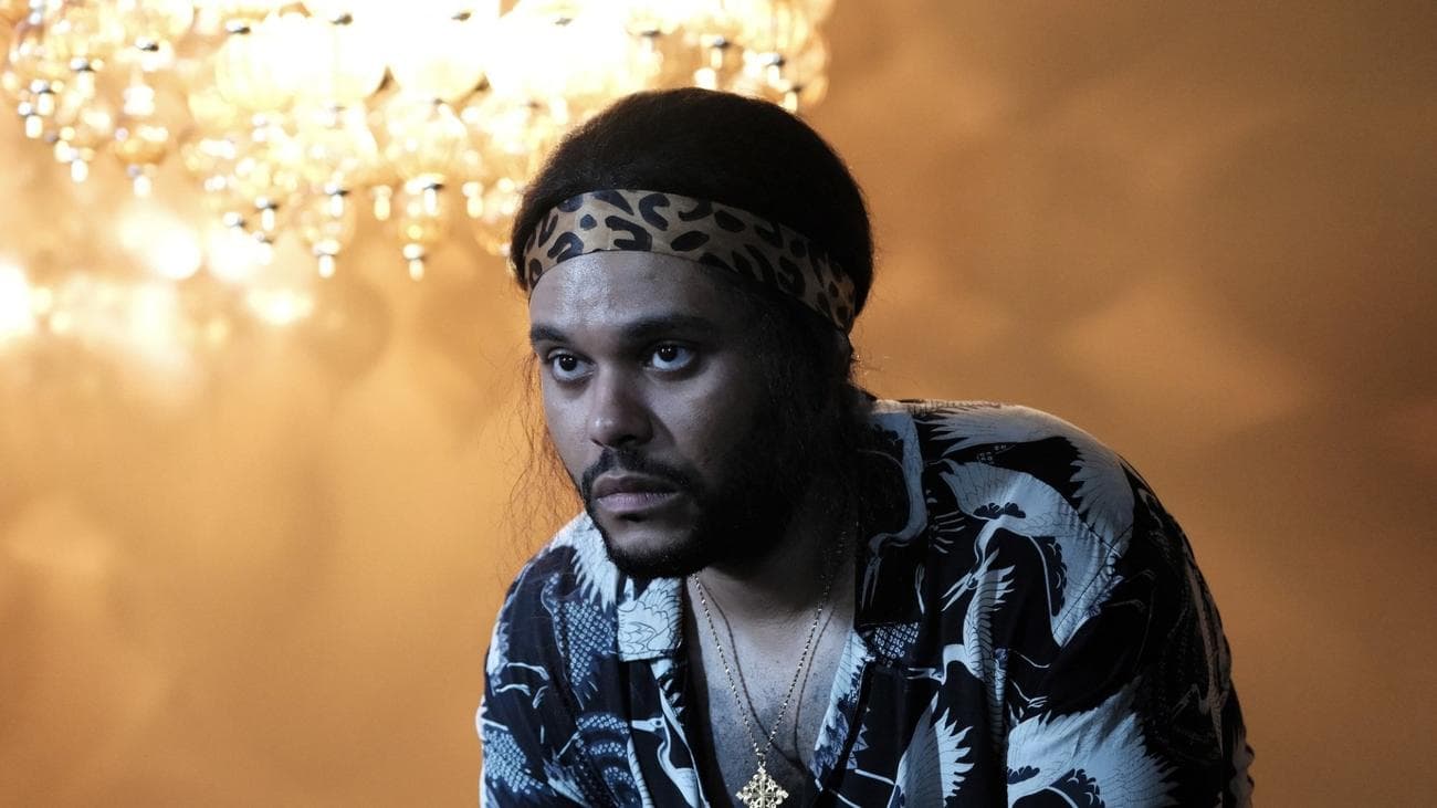 Ένας ατημέλητος άντρας σε ένα δωμάτιο που φωτίζεται από έναν πολυέλαιο.