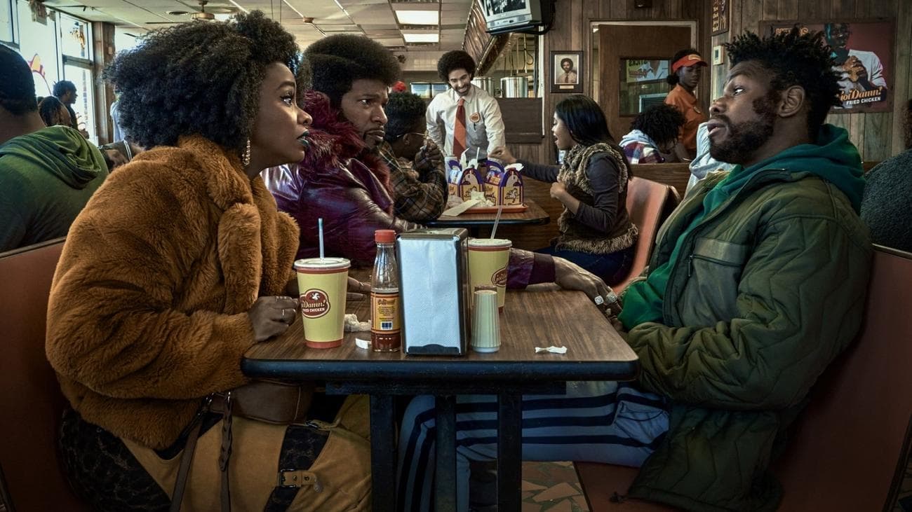 Δύο άντρες και μια γυναίκα κάθονται σε ένα γεμάτο τραπεζαρία. 