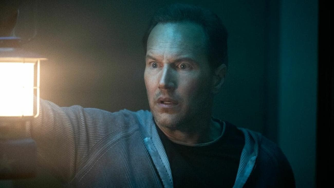 Ένας άντρας κρατά ένα φανάρι σε ένα σκοτεινό δωμάτιο ενώ φαίνεται φοβισμένος. 