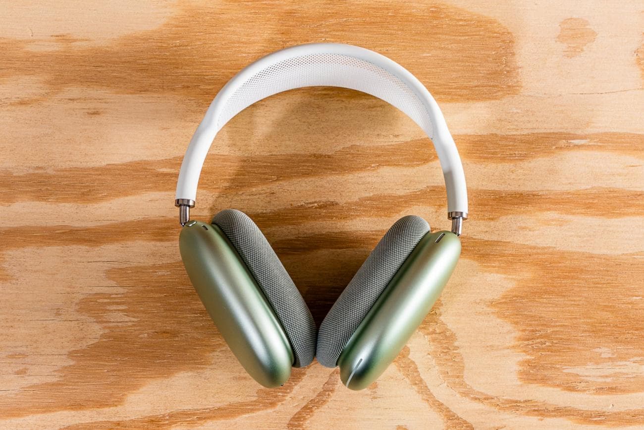 A pair of Apple AirPods Max headphones on a wooden surface. 