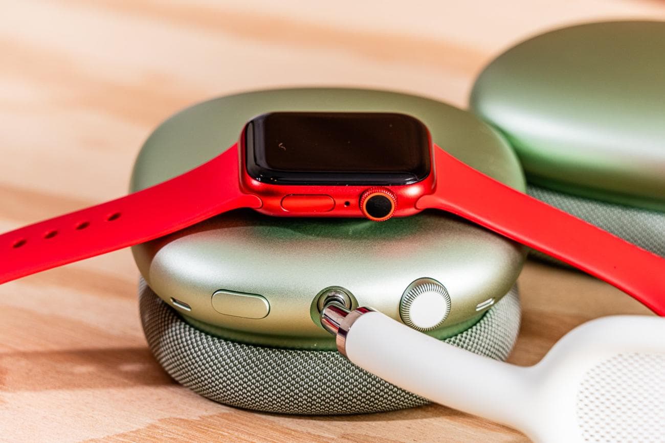 A red Apple Watch on an AirPods Max ear cup.