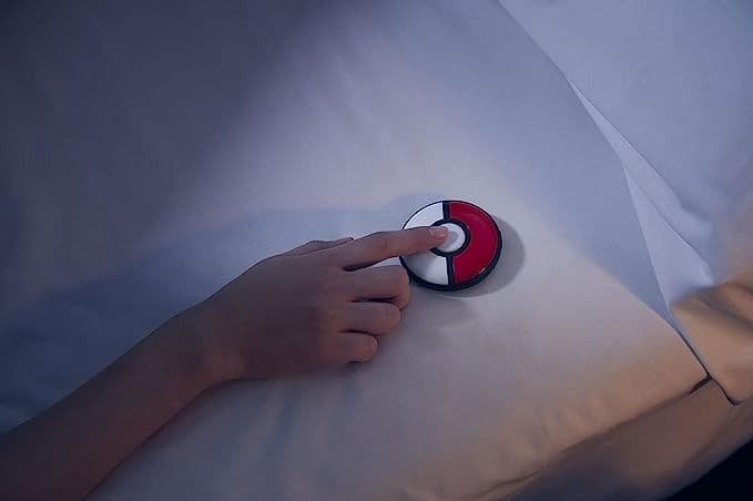 χέρι που αγγίζει αξεσουάρ pokeball σε λευκά σεντόνια