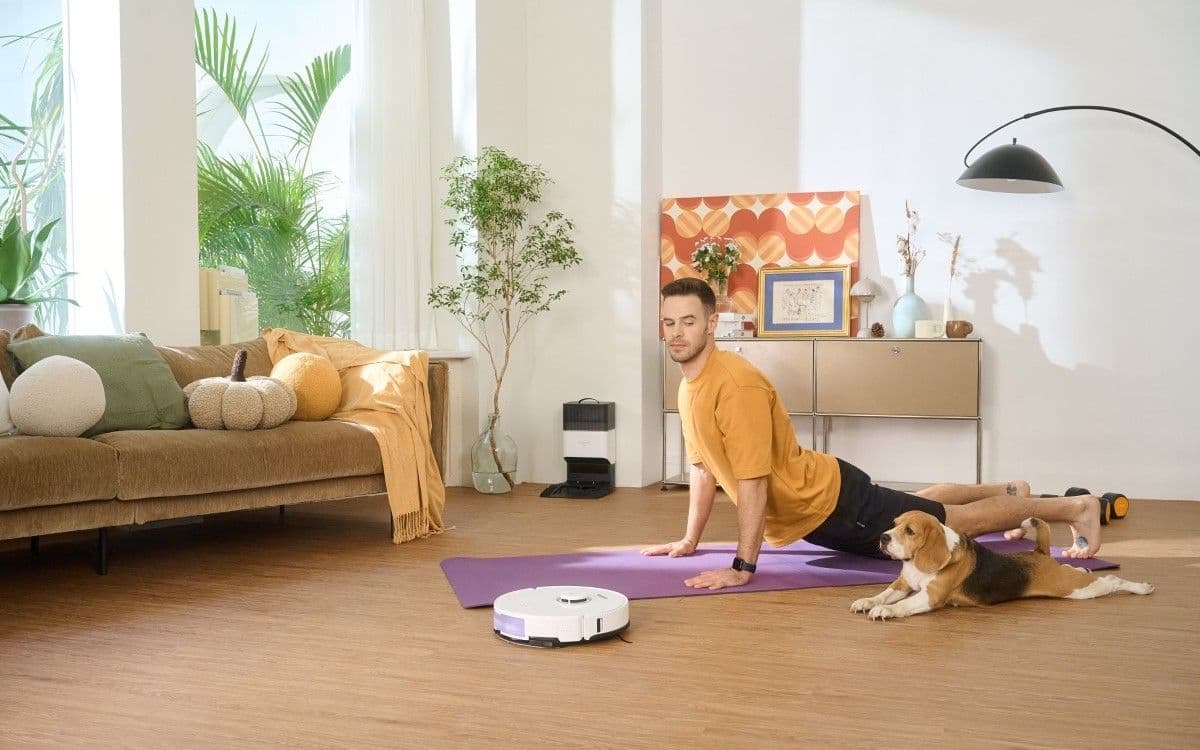 Άντρας που ασκείται με τον σκύλο του, με το Roborock S8+ στο πάτωμα 