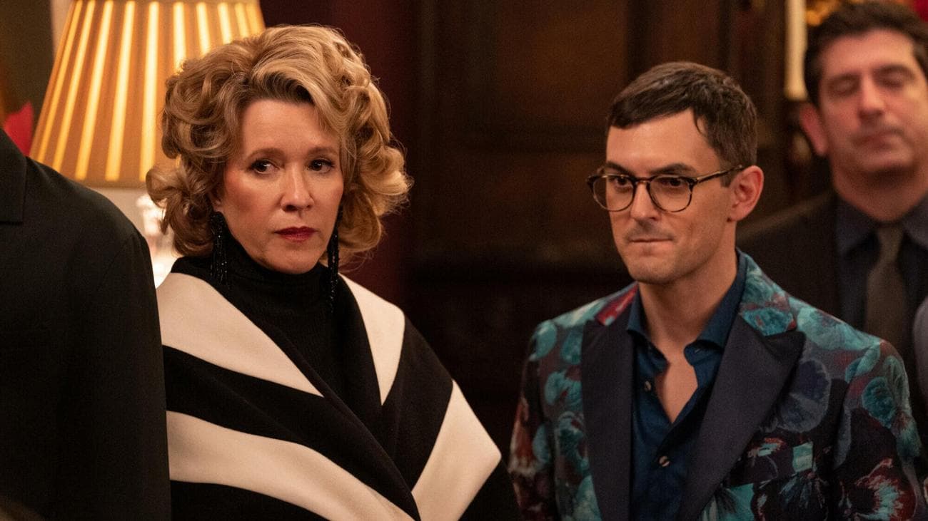 An older woman wearing a black and white striped coat, and a young man wearing a green blazer. 