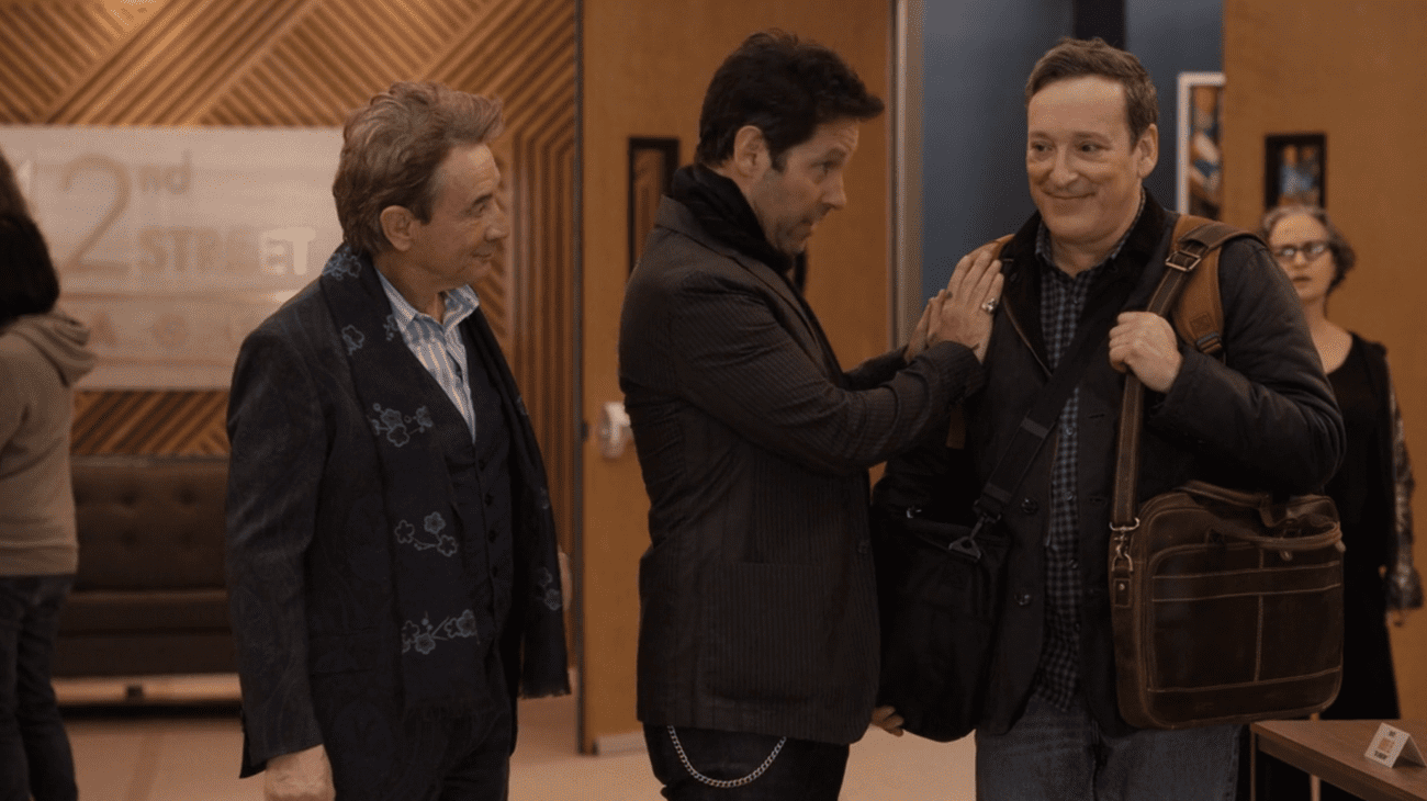 Three men stand during a meeting. 