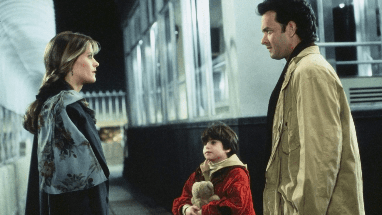 Two adults and a child talk near a building. 