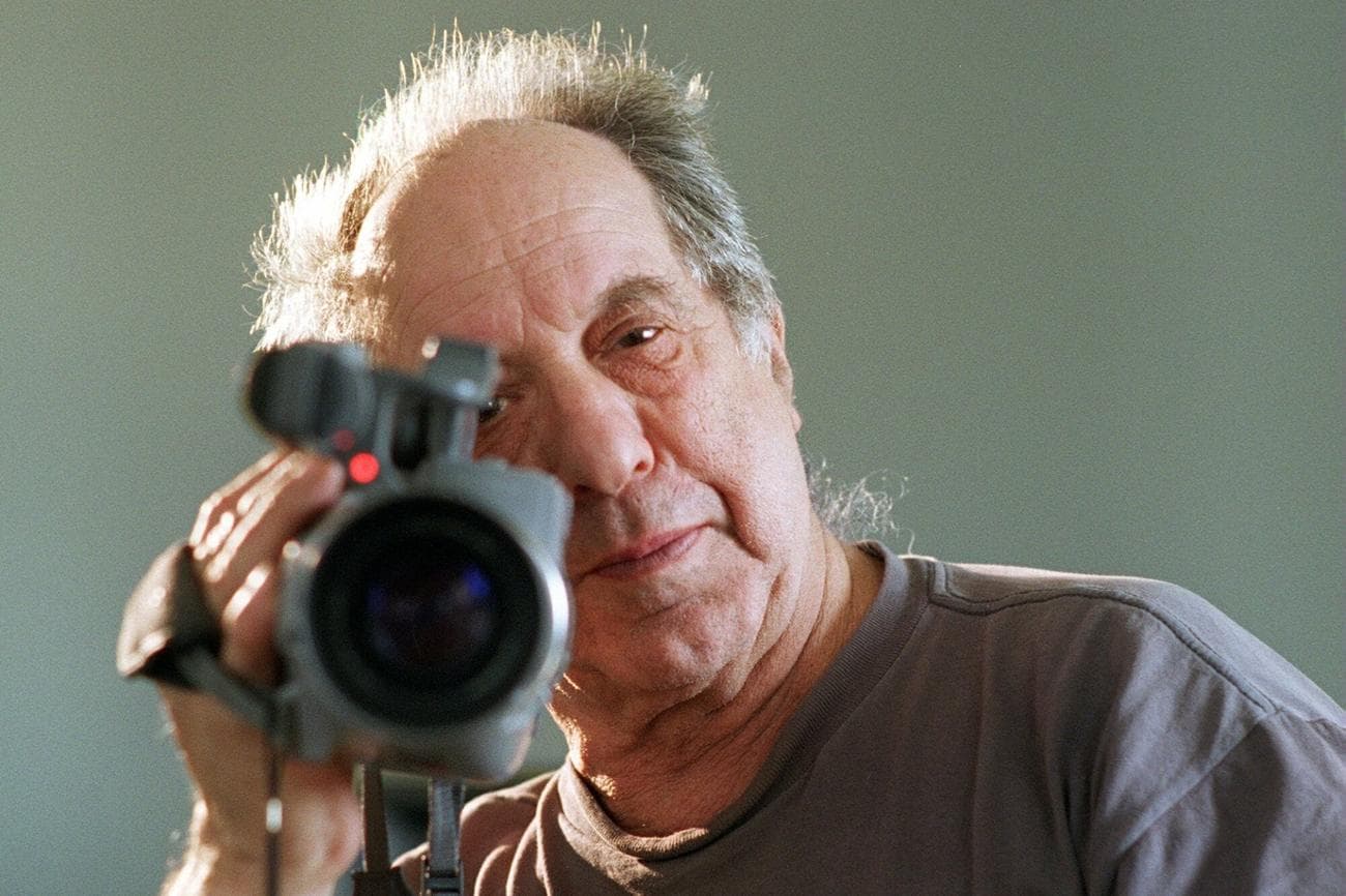 Photographer and filmmaker Robert Frank looks down a camera.