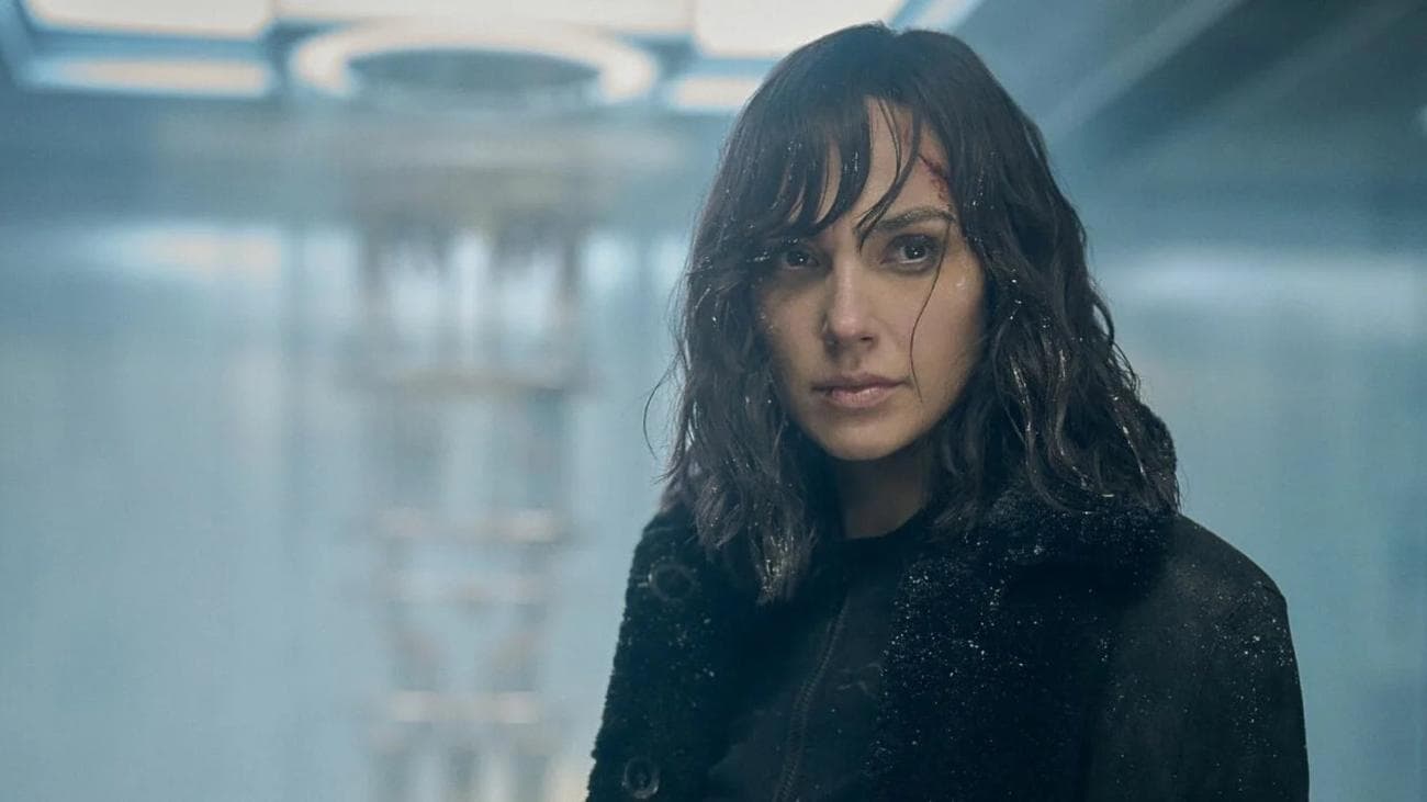 Μια γυναίκα είναι βρεγμένη από τη βροχή φορώντας ένα μαύρο σακάκι. 