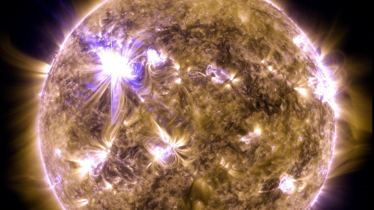 A NASA image of the sun with a bright solar flare in the upper left.