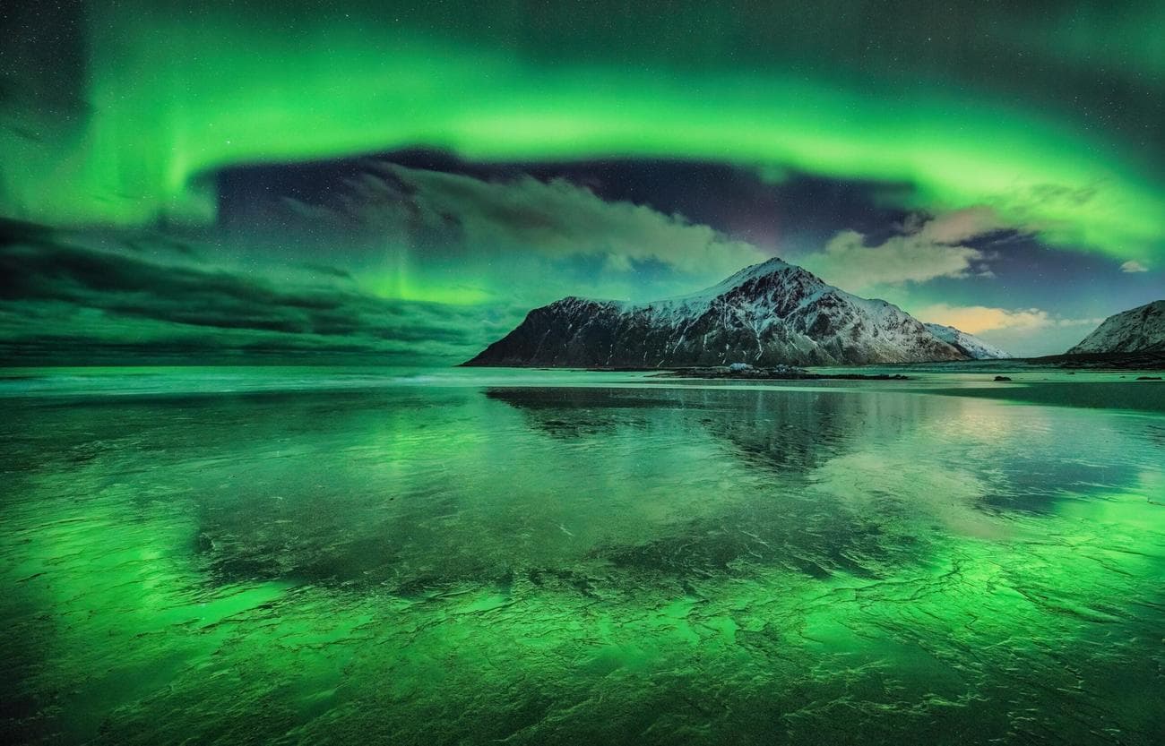 Green aurora encircling a mountain and lake
