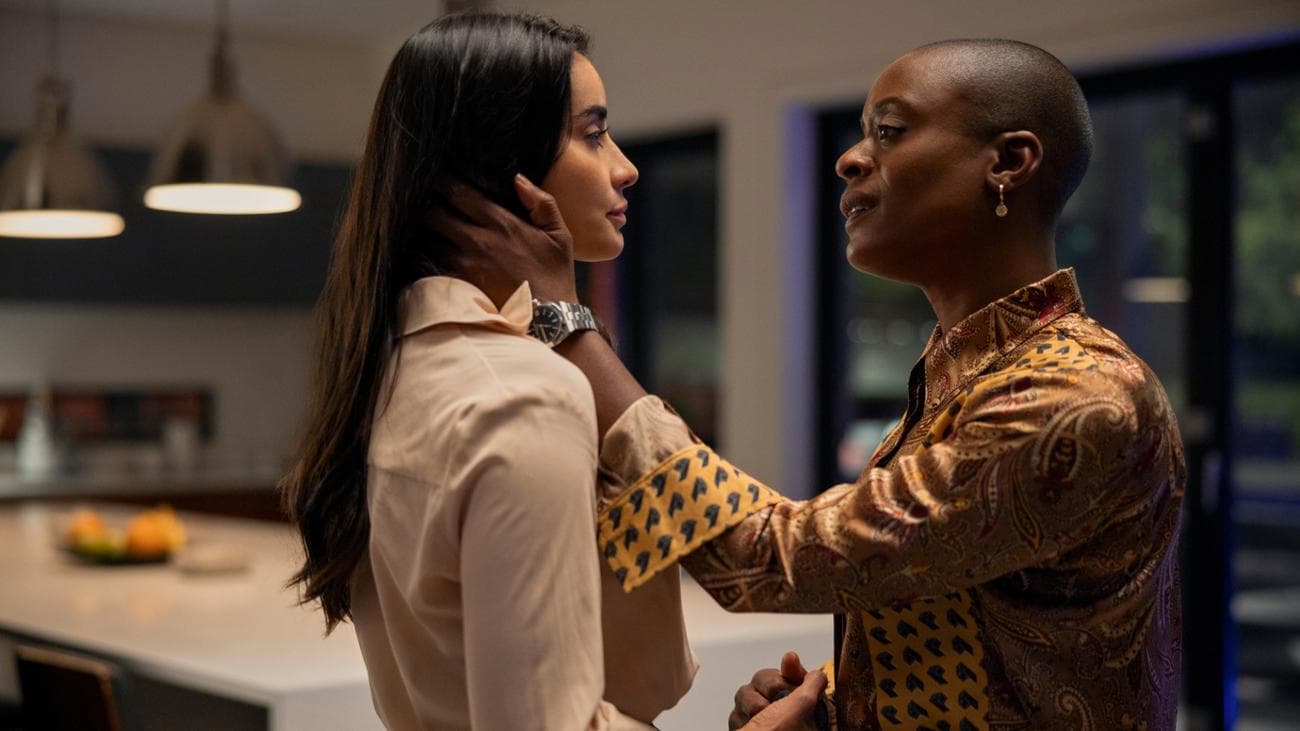 Μια γυναίκα κρατά το πρόσωπο μιας άλλης γυναίκας με το χέρι της σε μια κουζίνα.