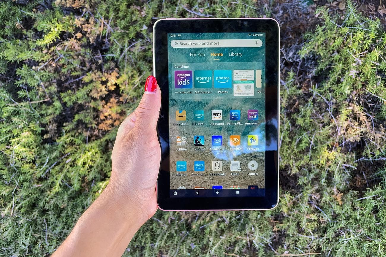 A hand holding Amazon's Fire 7 tablet while its screen is turned on.