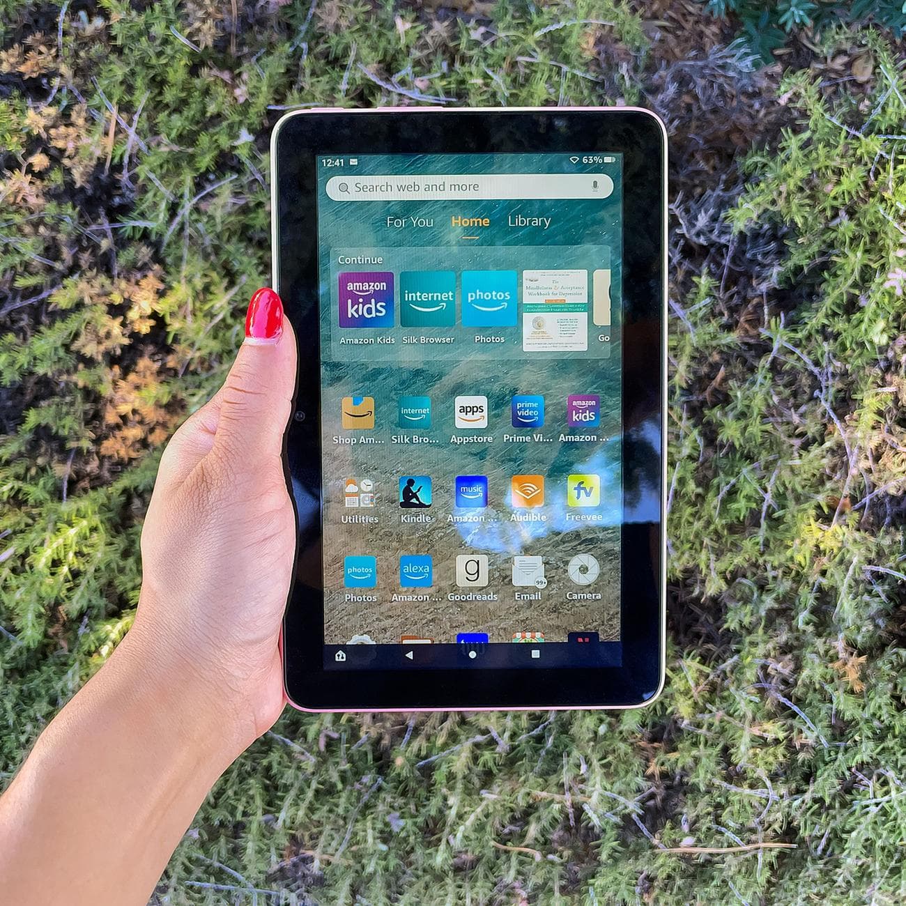 A hand holding Amazon's Fire 7 tablet while its screen is turned on.