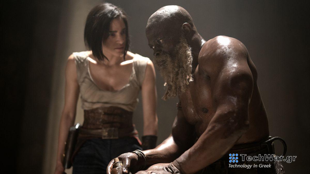 Kora tries to persuade a shirtless Titus to join her cause in Rebel Moon Part 1