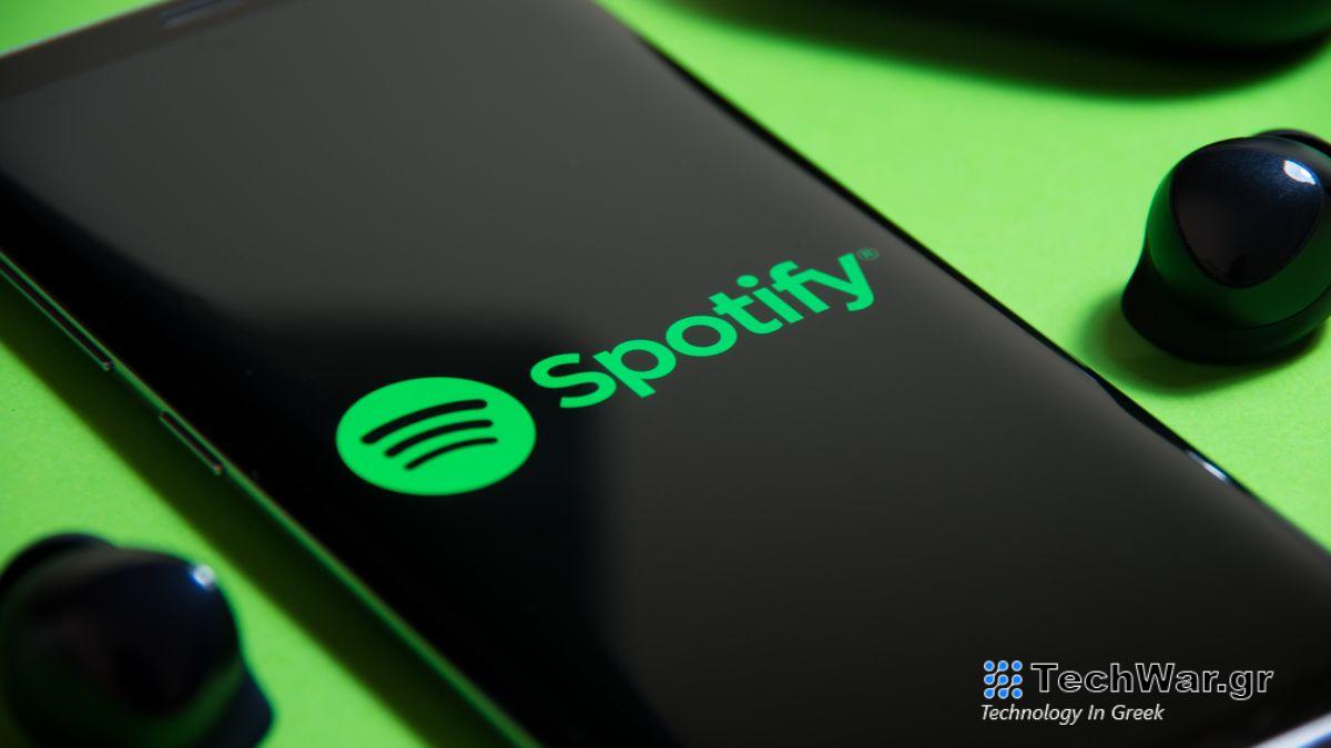 Spotify app on a smartphone next to a pair of true wireless earbuds