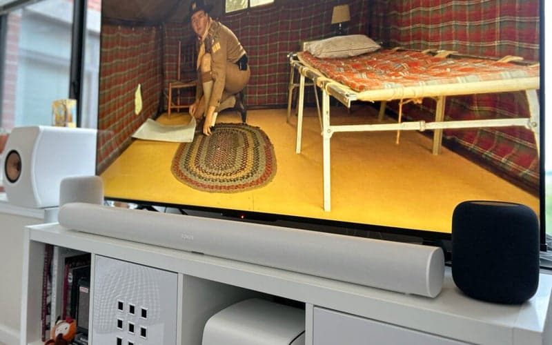 Sonos Arc soundbar in front of a TV flanked by HomePods