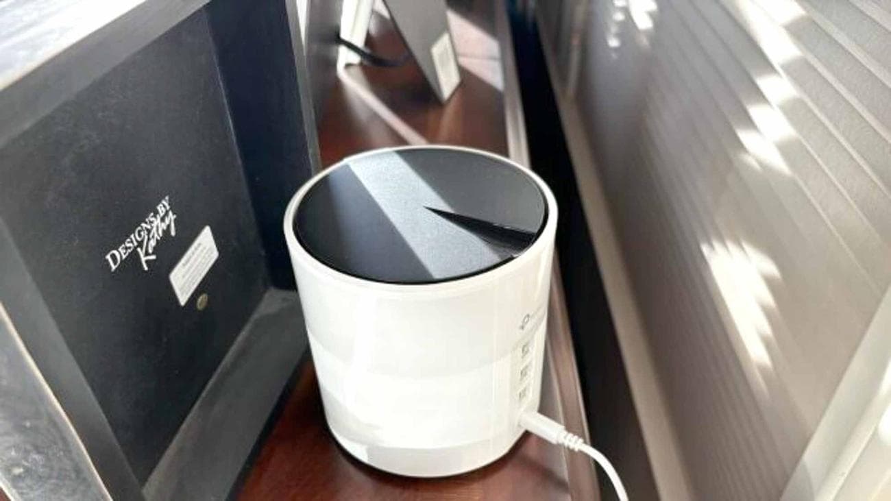 Ένας δρομολογητής πλέγματος TP-Link Deco X55 κρυμμένος πίσω από μια κορνίζα σε ένα ράφι