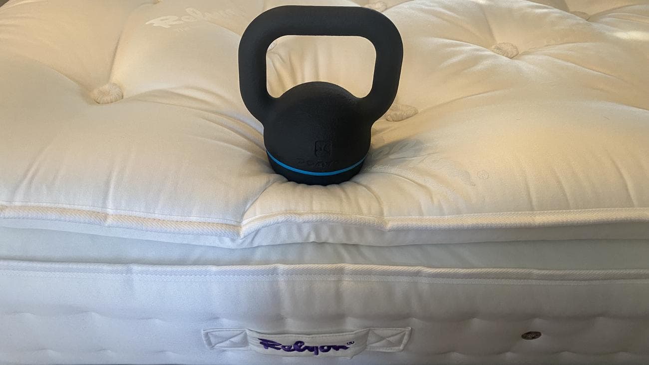 Relyon Bridgwater Dunlopillo Latex Mattress review image shows a heavy black weight placed on the very edge of the mattress to test the perimeter support