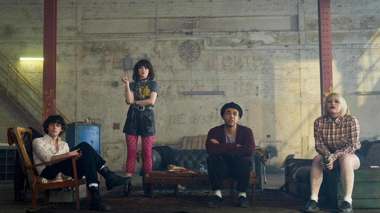 Four young people sit and pose in a warehouse.