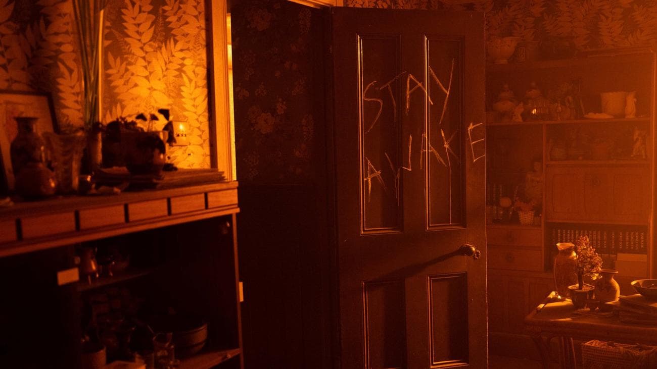 Οι λέξεις "Μείνε ξύπνιος" είναι σκαλισμένα σε μια πόρτα στην τηλεοπτική εκπομπή "Η Γυναίκα στον Τοίχο"