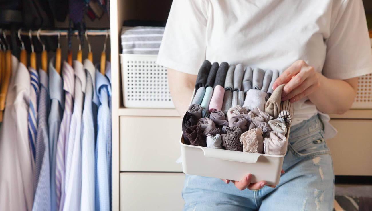 Μια νεαρή γυναίκα που οργανώνει τα ρούχα της σε ένα καλάθι