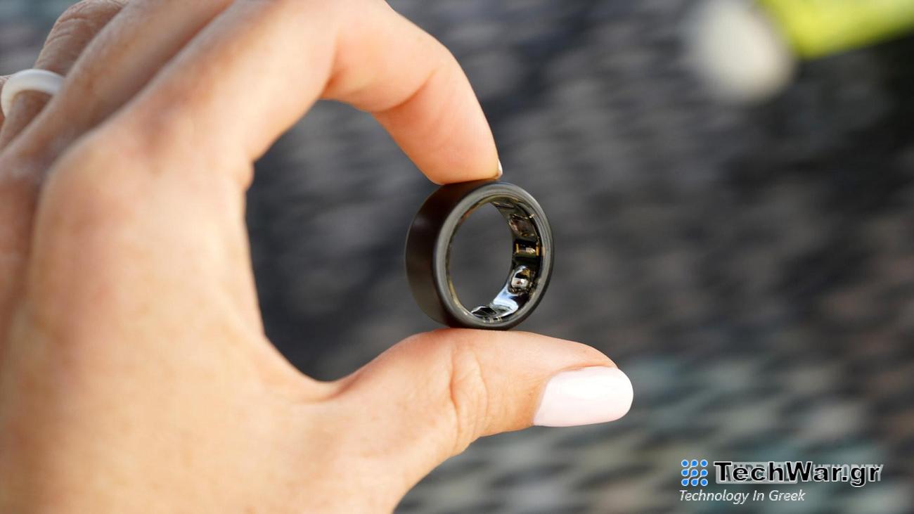 A user holds and Oura Ring 3 between two fingers, displaying the devices sensors.