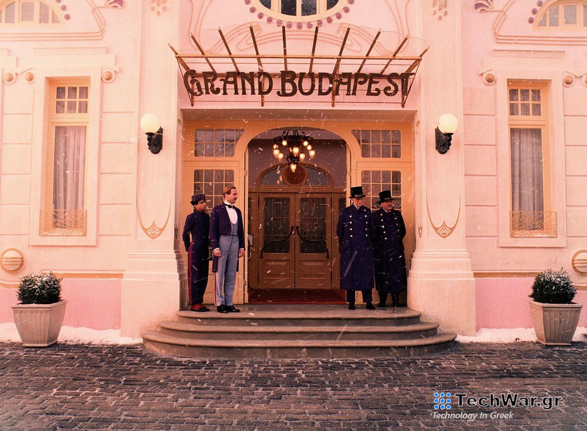 Zero (Tony Revolori) and M. Gustave (Ralph Fiennes) stand on either side of the doors to The Grand Budapest Hotel