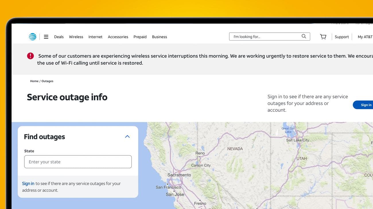 A laptop screen on an orange background showing the AT&T website