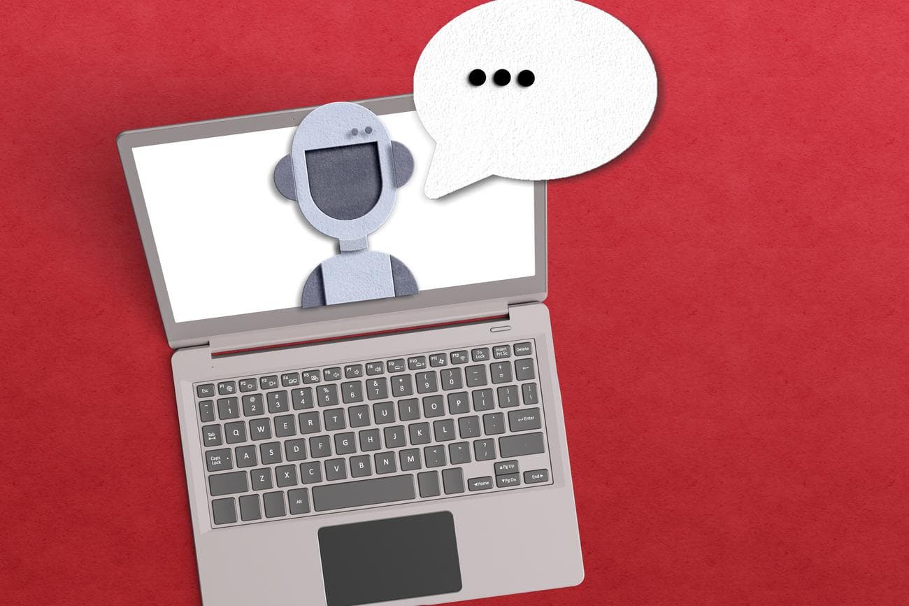 Έννοια πράκτορα AI με ρομπότ μέσα σε φορητό υπολογιστή με φωνητική φυσαλίδα σε κόκκινο φόντο.