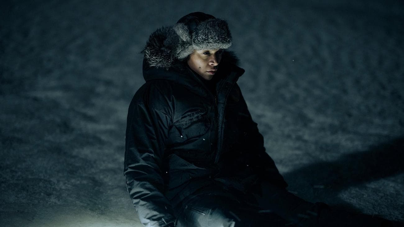 Η Κάλι Ρέις κάθεται στο σκοτάδι στον πάγο, φωτισμένη από το φως του πυρσού.