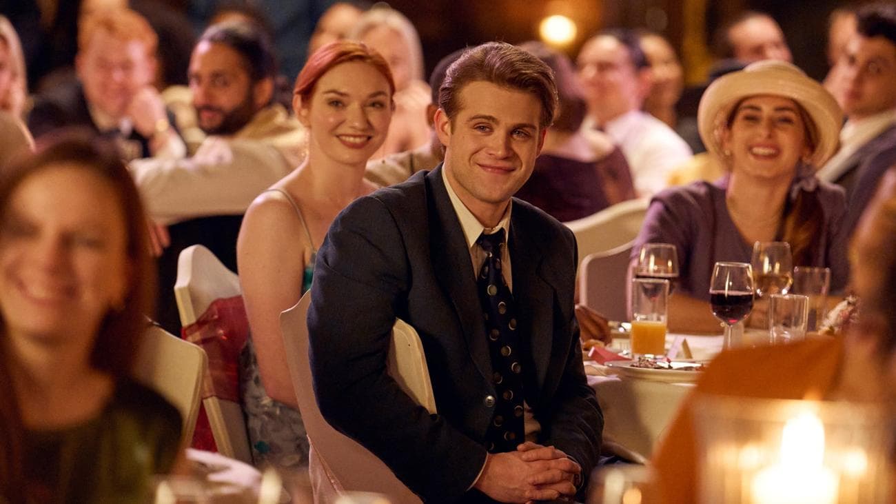 Ένας νεαρός άνδρας κάθεται σε ένα πλήθος γάμου κατά τη διάρκεια μιας ομιλίας.