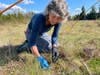 a woman wearing latex gloves kneels in the grass
